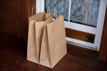 Kraft paper bags at entrance to country house. Contactless delivery of goods and products during covid-19 epidemic. Home delivery of food grocery bags left at door for Corona virus spreading safety.