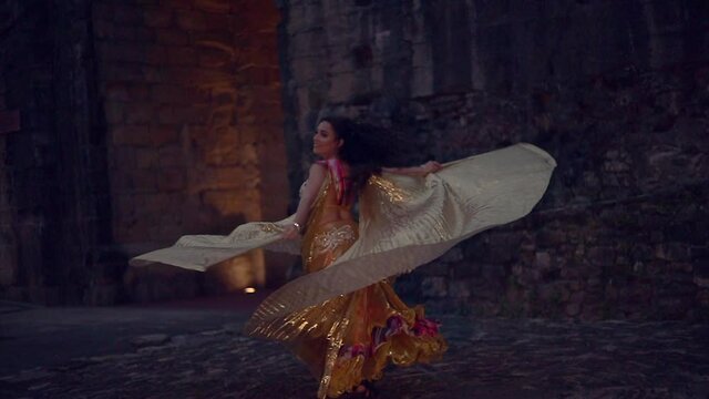 Bailarina de danza del vientre con alas doradas bailando por la noche