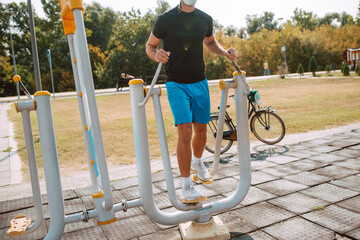 Close-up of a handsome male caucasian athlete training on a stepper in the outdoor gym. Muscular...