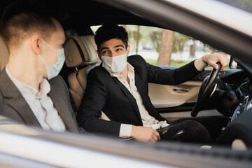 coronavirus, pandemic, epidemic, infection. Sitting in the car wearing protective masks from covid 19, talking about work, strict business suits