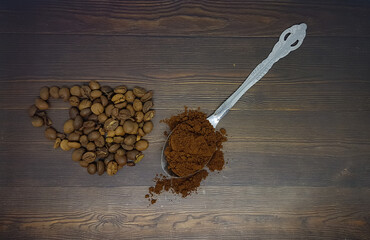 Coffee beans and coffee powder in a spoon with wooden background. 
