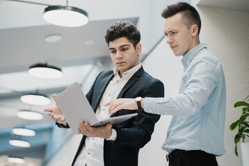 Managers of Caucasian appearance working on a laptop do a new task on the website of their company, new ideas for a strategy of development in the markets.