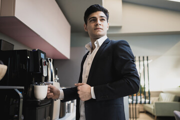 business professional manager businessman pours coffee from coffee machine in the office. strict business suit with a short haircut. European appearance coffee break