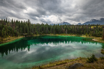 The trees and clouds reflected over the fourth lake at the Valley of the Five Lakes at Jasper, Alberta, Canada