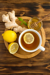 Top view of green tea with lemon, honey and ginger in the wooden cutting board