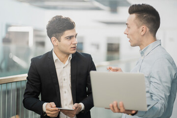 meeting of partners, discussing new plans for the development of the site. confident stylish young businessmen managers working on laptop in bright office.