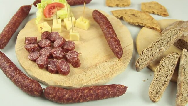 slider view of chefs hands serving a typical South Tyrolean snack plate like Tyrolean smoked sausage on a wooden cutting board accompanied by kaminwurz and paarl type bread