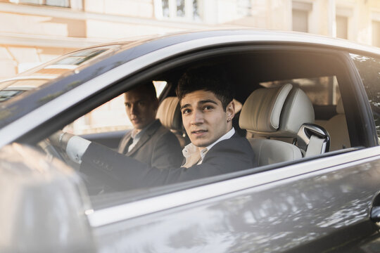 confident stylish young male businessmen managers Caucasian appearance sitting in the car and driving his favorite car. business formal suit goes to work good mood.