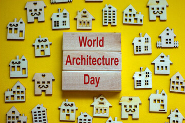 Wooden blocks form the words 'World Architecture Day', miniature wooden houses. Beautiful yellow background, copy space. Business concept.