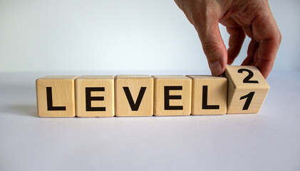 Time for Level 2. Hand is turning a cube and changes the word 'level 1' to 'level 2'. Beautiful white background. Business concept. Copy space.