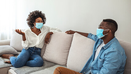 Two  friends in social distancing sitting on sofa. Best friends having coffe together while separated by social distancing on sofa at home. Preventing covid 19 coronavirus pandemic infection spread.