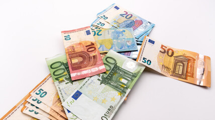 several Euro cash banknotes scattered on the white background