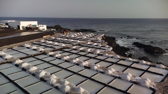 A dinamic panning shot of saltworks beside the sea in a rocky coast at the evening