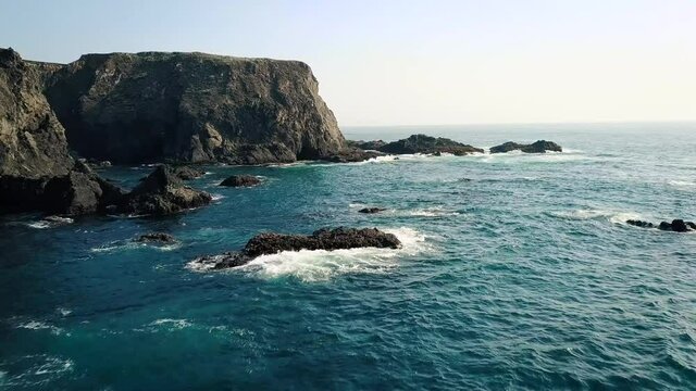 Aerial view of ocean waves crashing the California rocky coast.