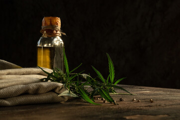Hemp oil, textile and cannabis plant on wooden table