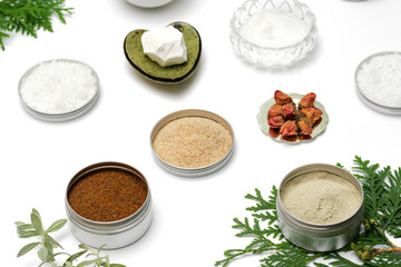 Ingredients for the production of cosmetics on a white background. Clays, wax, herbal powders, dried flowers, raspberry ketone, menthol crystals. Natural cosmetics concept.