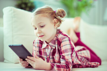 Fototapeta na wymiar Portrait of cute little child girl with tablet at digital homeschooling