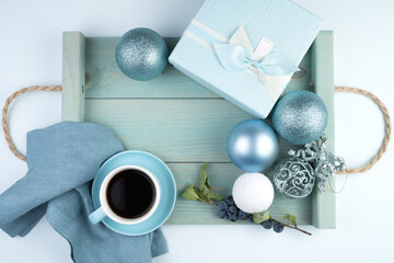 Happy new year 2021, festive composition with a Cup of coffee, gift box, Christmas balloons and a tray in a soft blue color. The view from the top. The concept of the new year 2021 and Christmas.