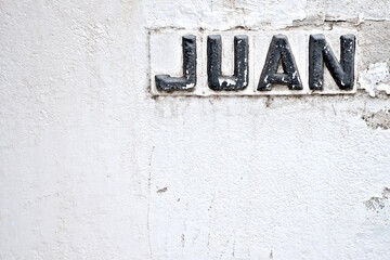 Spanish name Juan (English name John) a black word on a white weathered wall.