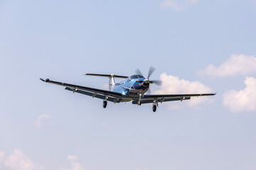 Single-engine blue airplane flying on a sunny day in the blue sky. The plane rises after takeoff.