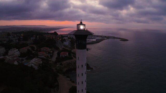 Superb aerial Drone footage of sunset at the lighthouse on the Gold Coast of Spain, Torredembarra. Drone circling around the lighthouse with amazing sky in background