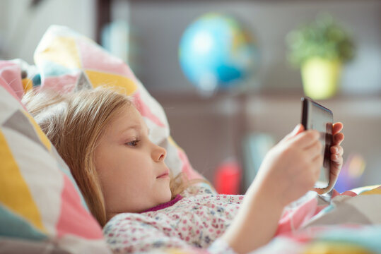 Portrait of cute little preschool child girl laying ill with tablet at homeschooling