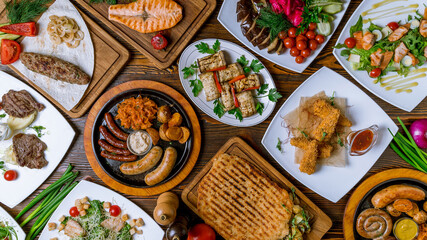 Different meals at table top view. assorted sausages with sauces, eggplant rolls, salmon steak, cheese sticks, salad with salmon, Vienna schnitzel from veal