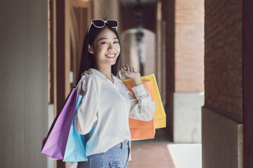 Young Asian women happily carry colorful shopping bags to shop in the mall or shopping center, Sale day, Happy shopping concept.