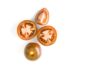 Top view Kumato - dark tomato variety, whole, halves and slices on a light white background.