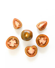 Top view Kumato - dark tomato variety, whole, halves and slices on a light white background.