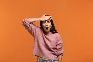Crap, I forgot to do this. Portrait of worried stunned woman in pink sweater slapping forehead with...