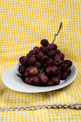bunch of red organic grapes on a tray and tableclothbackground
