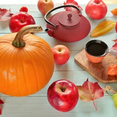 Naklejka na ściany i meble Thanksgiving Day. Autumn tea. Autumnal vegetable and fruit abundance. A cup of tea, teapot, pumpkins, apples and autumn leaves on a blue wooden background.View from above.Autumn mood.Fall season