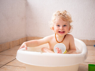 Happy one year old baby boy enjoying a bath on the balcony