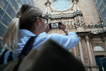 Unrecognizable female tourist taking picture of sight