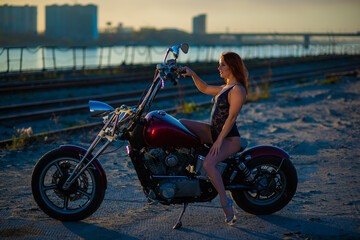 Fototapeta na wymiar Red-haired woman in sexy lingerie in high heels sits on a motorcycle