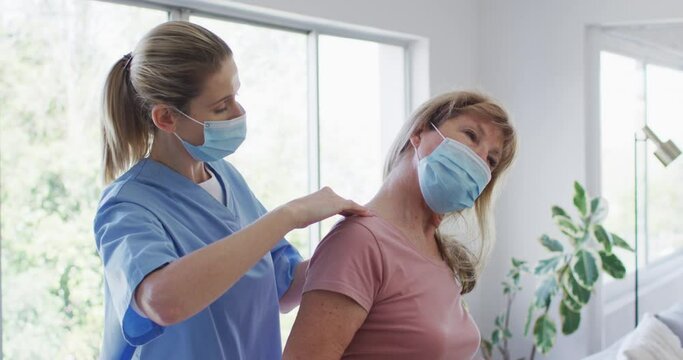 Female health worker stretching neck of senior woman at home