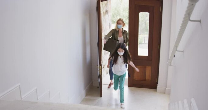 Mother and daughter wearing face masks entering the house