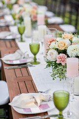 dinner tables with white cloth, served with porcelain and green glasses. Georgeous wedding table decorated with flowers