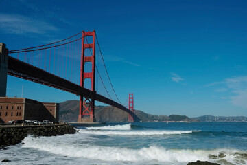 Fototapeta na wymiar Golden Gate Bridge, San Francisco, California USA. Classic panoramic view, famous landmark. Touristic attraction, travel destination at sunny surf beach day, of blue clear sky. Surfing next Fort Point