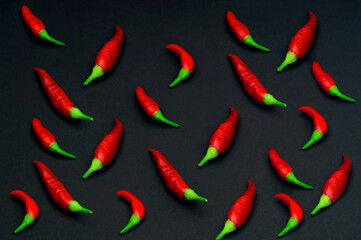 Pattern of small red peppers on dark background. Creative copy space.