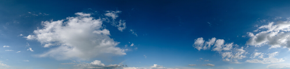White cumulus clouds and rainbow in blue sky panoramic high resolution background
