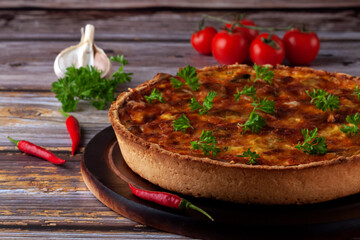 French quiche with chicken and mushrooms on wooden background