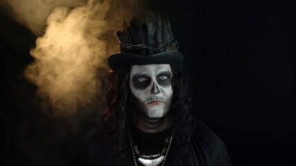 Creepy man with skeleton makeup in top-hat. Guy making faces, toothy smile. Halloween thematic party