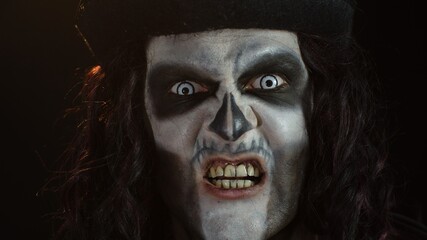 Frightening man in skeleton Halloween makeup screaming, shouting, making faces, trying to scare