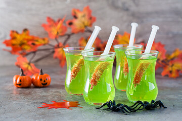 Halloween cocktails. Syringes with blood in glasses with green lemonade on the table. Festive decorations