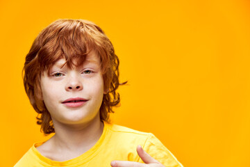 red hair boy on an isolated background in a yellow t-shirt