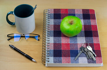 Study notebook with glasses, pen, breakfast cup and apple