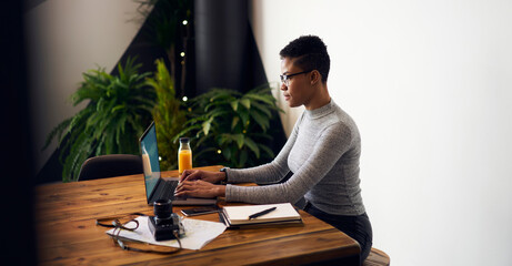 Focused ethnic female entrepreneur typing on laptop