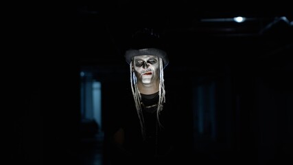 Frightening man in carnival skull Halloween makeup of skeleton looking creepy at camera on parking